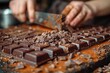 A chef's hands are meticulously chopping up chocolate bars for dessert preparation, focusing on the action