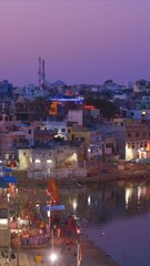 Wall Mural - View of famous indian hinduism pilgrimage town sacred holy hindu religious city Pushkar with Brahma temple, aarti ceremony, lake and ghats illuminated at sunset. Rajasthan, India. Horizontal pan