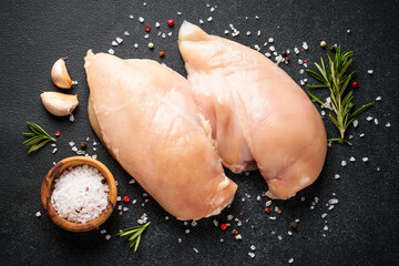 Wall Mural - Chicken meat. Raw chicken breast with spices at black table. Top view.