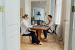 © muse studio - Two focused professionals work across from each other, their laptops and phones at hand in a bright room.