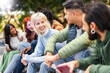 A multicultural group of students enjoys a lively discussion and shared laughter in an outdoor campus setting - Young people lifestyle, joy of youthful camaraderie and diverse student life.