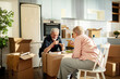© Marko Geber - Senior couple eating pizza on moving boxes at home