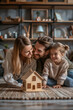 © S photographer - Parents and daughter playing with a wooden house model in the room.