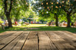 Empty wooden table in summer background with the blurred green garden and party in the background.