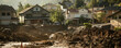 mudslide engulfing a residential neighborhood, with homes buried under a torrent of mud and debris.