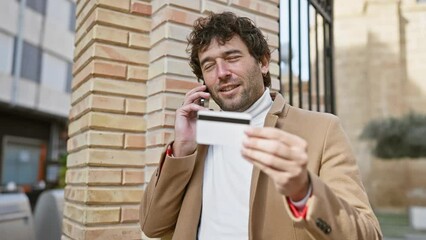 Poster - A handsome young man talks on the phone while holding a credit card on a city street