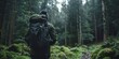 A man is walking through a forest with a backpack on his back. The forest is lush and green, and the man is enjoying the peacefulness of the woods