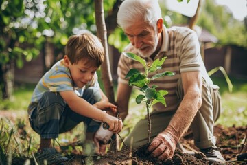 A grandfather with his little grandson is planting a sprout of a green tree, sharing experience and caring with the younger generation