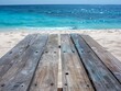 a wooden table on the beach, with the water next to it 