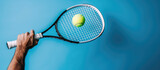 Fototapeta  - Tennis player is holding racquet and hitting ball on blue background
