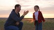Daughter father special handshake greeting clapping hands gesture expressing strong close family relationship. Baby girl kid child man dad at sunset sunrise in field happy relatives hugging cuddling.