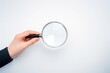 A hand holding a magnifying glass over a white background