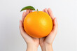 Hand holding a ripe orange fruit against a white background, showcasing its vibrant color and juicy freshness, rich in vitamin C and bursting with flavor.