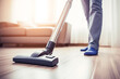 In the background of a living room, a vacuum cleaner tackle dust and dirt on carpets and floors for thorough housekeeping.