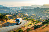 Fototapeta  - Large truck on a curved road amidst rolling hills during sunset