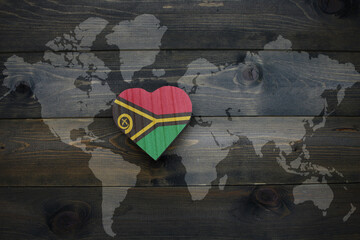 Wall Mural - wooden heart with national flag of Vanuatu near world map on the wooden background.