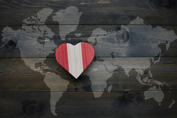 Wall Mural - wooden heart with national flag of peru near world map on the wooden background.