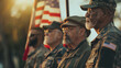 A diverse group of veterans from different military branches and generations standing solemnly around a flagpole, with the American flag hoisted high. The morning light casts soft