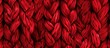 Close-up detail of intricate red knitted fabric showcasing a beautiful braid pattern design