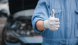 © sorapop - Mechanic in jumpsuit checks car gives thumbs up. Expertise in repair and service ensuring safety and quality. Skilled technician working in automotive industry smiling.