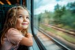 © Kate Mayer - A delighted little girl peers out of the train window as it travels through Europe, marveling at the passing scenery
