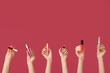 © Pixel-Shot - Female hands with lipsticks and mascara on dark red background