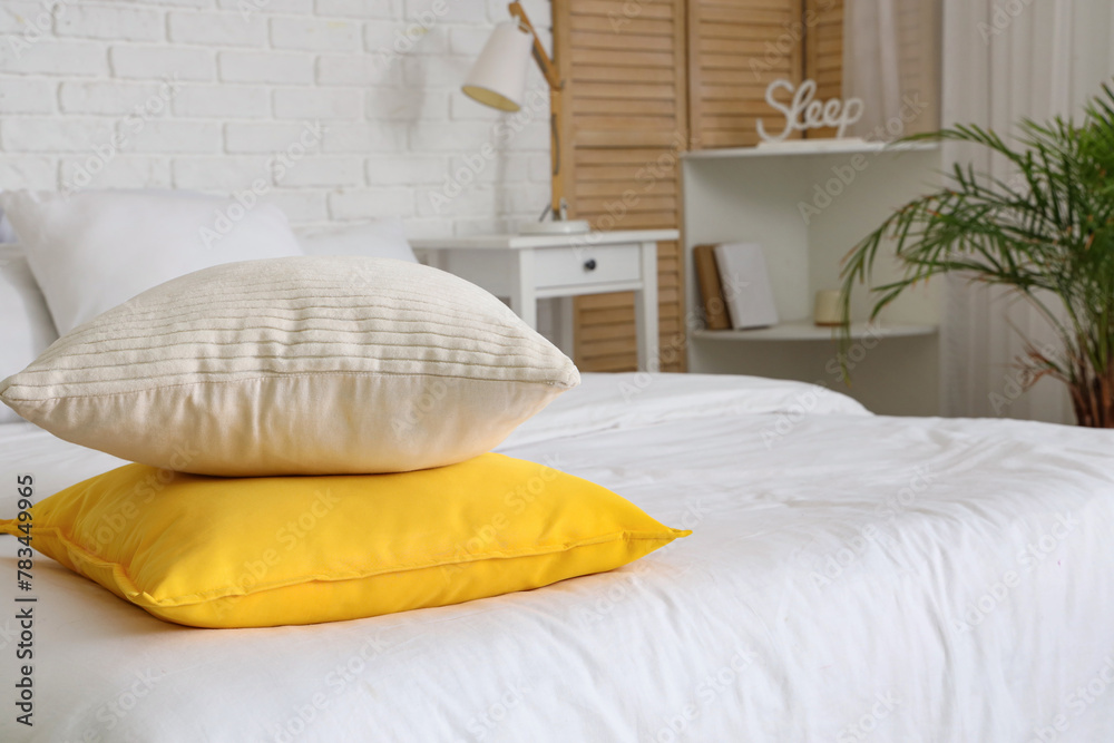 Soft pillows on cozy bed in bedroom, closeup