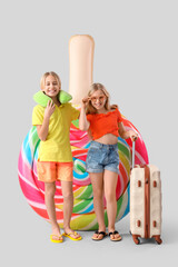 Wall Mural - Cute little kids with inflatable mattress in shape of candy and suitcase on grey background