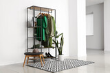 Fototapeta Tulipany - Rack with stylish female clothes, shoes and houseplant in interior of light room