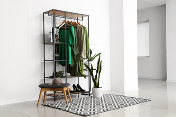 Wall Mural - Rack with stylish female clothes, shoes and houseplant in interior of light room
