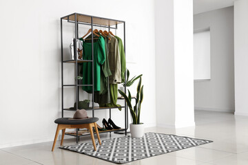 Sticker - Rack with stylish female clothes, shoes and houseplant in interior of light room