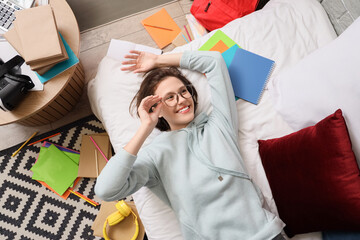 Canvas Print - Female student with copybooks lying in bedroom, top view