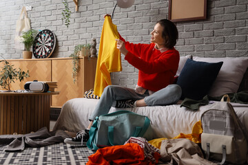 Poster - Female student with clothes sitting in messy bedroom