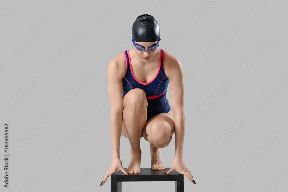 Young female swimmer on light background