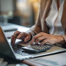 A Close-up View Of A Businesswoman Working On Financial Reports Using A Calculator And Laptop, Managing Budgets And Investments.