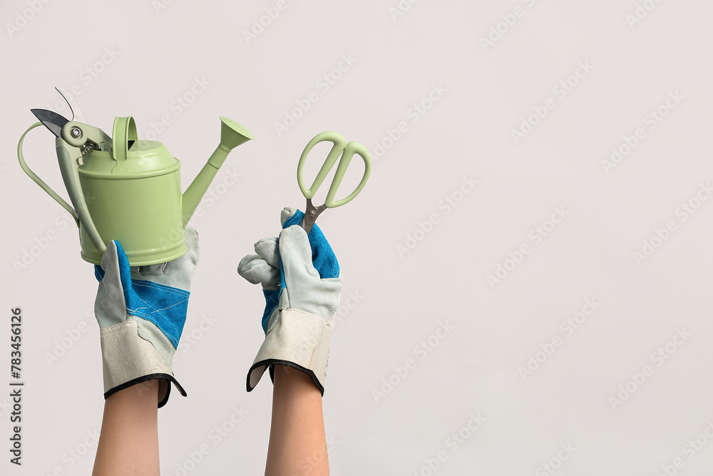 Female hands in gloves holding watering can and scissors on white background