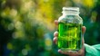 A closeup of a hand holding a glass jar filled with a vibrant green liquid. The liquid is derived from energy algae and is being tested as a potential biofuel source offering a promising .