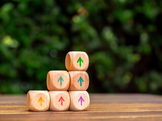 Poster - Multi Colors rise up arrows on wooden cube blocks stack, bar graph chart steps on green leaves background with copy space. Profit, benefit, income, market trends and business growth process concepts.