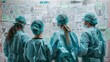 © Justlight - A team of healthcare workers wearing scrubs and personal protective equipment standing in front of a whiteboard filled with diagrams and notes as they strategize and problemsolve. .