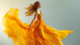 Fototapeta Na sufit - Elegant woman dancing while soaring on the wind in a golden silk dress. On a grey background, a stunning model in a yellow gown waves. Joyful Young Woman in Imaginary Clothes