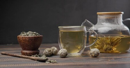 Wall Mural - Blooming flower tea ball brewing in a glass teapot with Hot boiling water on wooden background