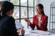 © amnaj - Asian Businesswoman discussing financial report with colleague. Positive business meeting with charts and graphs. Strategic planning and consultancy concept