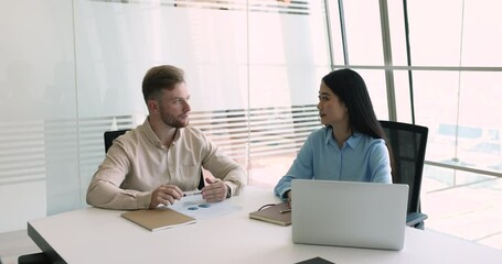 Sticker - Two multiethnic business colleagues talking at meeting table with laptop. Male boss speaking to young Asian employee woman. Customer and manager discussing project in office