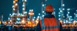 An oil refinery operator checking safety equipment and tools before starting his night shift, highlighted by the glow of emergency lights