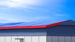 Large rental warehouse building with aluminium steel gable roof against blue sky background
