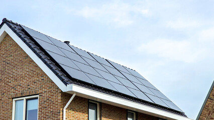 Wall Mural - Newly built houses with black solar panels on the roof against a sunny sky Close up of new building with black solar panels. Zonnepanelen, Zonne energie, Translation: Solar panel, Sun Energy