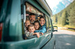Multi-generation family looking at camera outdoors at dusk, caravan holiday trip