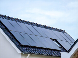 Wall Mural - black solar panels on the roof against a sunny sky Close up of new house with black solar panels. Zonnepanelen, Zonne energie, Translation: Solar panel, Sun Energy, Suburban area