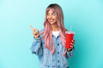 Wall Mural - Young mixed race woman drinking a fresh drink isolated on blue background pointing up a great idea