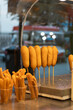 Vertical photograph of a Mexican snack stand at a fair food market, where a small business sells banderillas and churros to its customers in a plaza where tourists gather